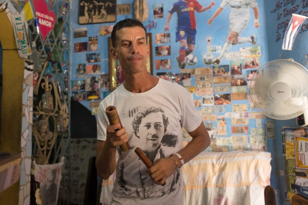 Bartender man with cuban dance pose wearing Pablo Escobar T shirt.