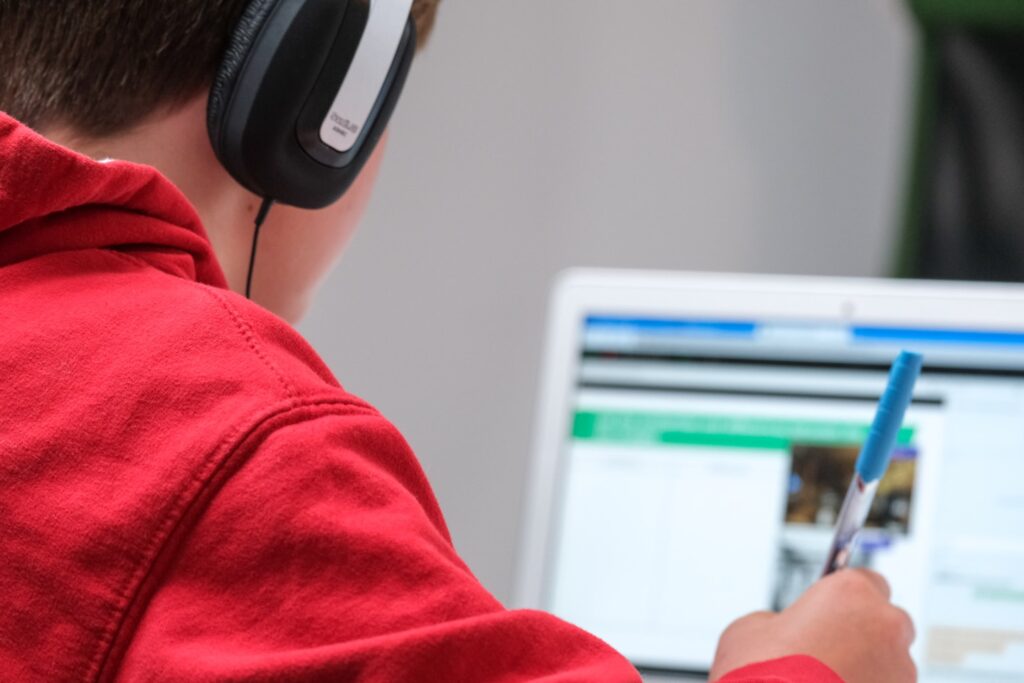 Home schooling during lockdown, boy working on school work with laptop and headphones during coronavirus covid 19 lock down. Remote learning through home schooling due to school closures has become commonplace in the UK in 2021.