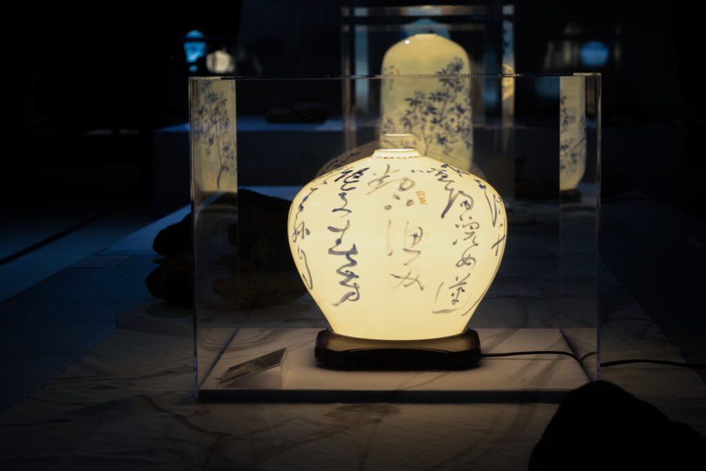 A glowing ceramic vase with calligraphy in a display.
